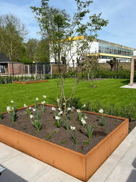 Rechthoekige cortenstalen bloembak aan het terras met bloemen