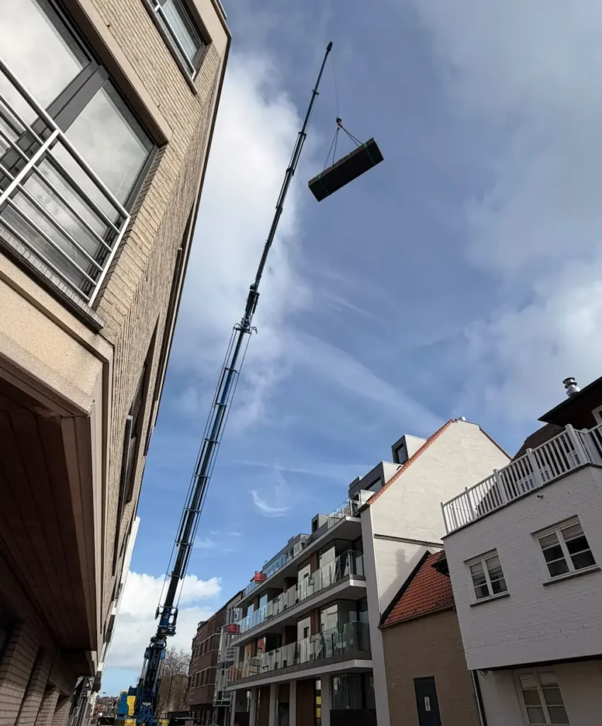 Cortenstalen bloembak die met een kraan over een gebouw wordt getild