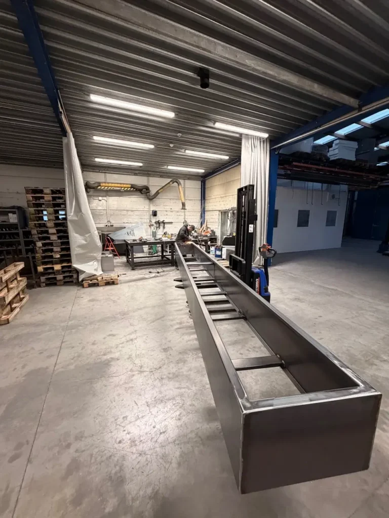 Cortenstalen bloembak en plantenbak van 6 meter lang, met lasser bezig aan de afwerking