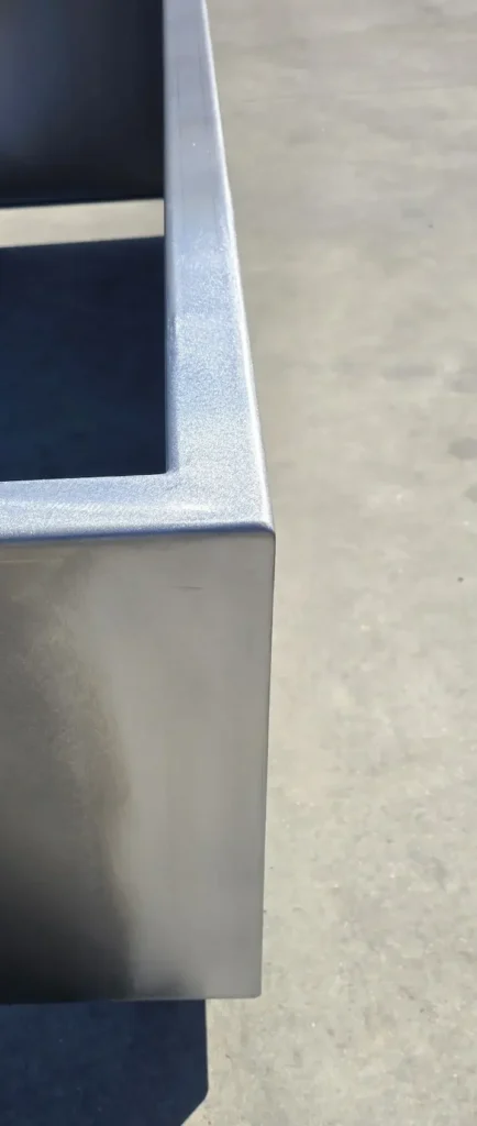 Detail van een afgewerkte hoek van een cortenstalen bloembak